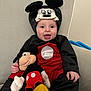 Christopher joined the competition — help win amazing prizes! baby, child, mickey_mouse_costume, plush_toy, smiling, tongue_out, indoors, chair, cushion, red_clothing, black_clothing, yellow_shoes, soft_toy, character_costume, cute, happy, portrait, person, seated, playful