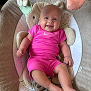 Mabel-Lilly is registered to the contest to win money with this photo: baby, smiling, infant, pink_clothing, plush_toy, baby_seat, comfort, happy, cute, indoor, child, face, portrait, soft_toys, relaxing, skin, foot, hand, sitting, expression