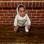 toddler, child, hoodie, sneakers, bench, wood, brick_wall, squatting, curious, indoors, casual_clothing, young_child, person, face, expression, fashion, floor, candid, portrait, small_child