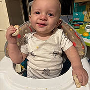 James joined the competition — help win amazing prizes! baby, high_chair, bread, crumbs, smile, happy, indoor, child, food, messy, toy, person, clothing, face, hand, furniture, plate, feeding, expression, home