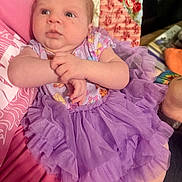 Amara joined the competition — help win amazing prizes! baby, infant, child, newborn, purple_tutu, dress, hands, face, portrait, quilt, blanket, fabric, pattern, arm, holding, indoor, seated, cute, curious_expression, person