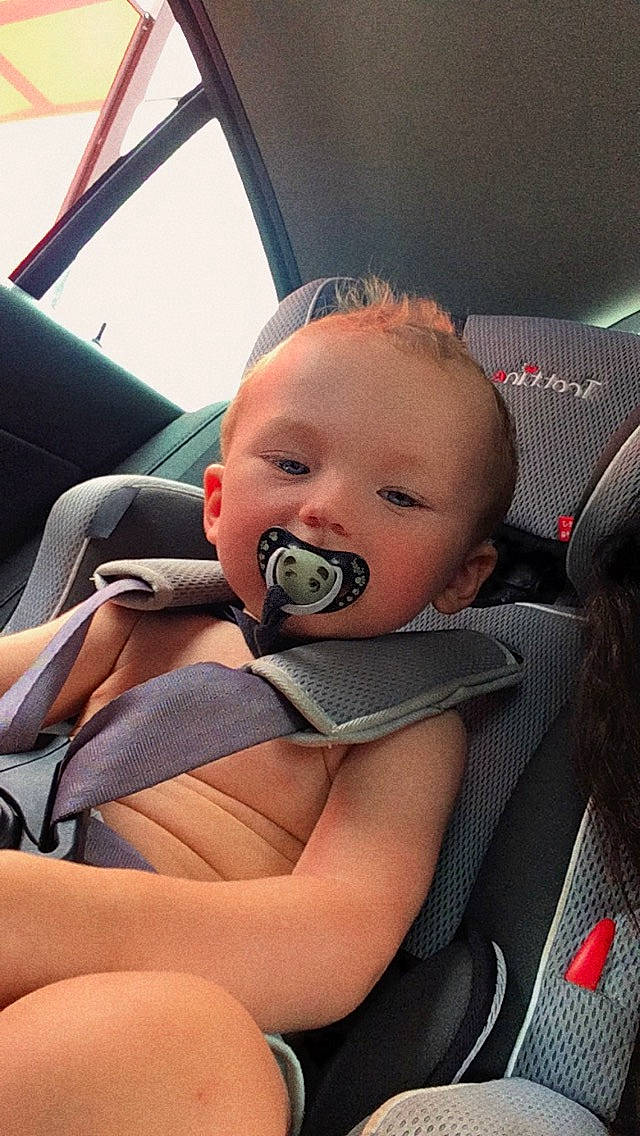 Ryan participe au concours pour gagner de l'argent avec cette photo : arm, automotive_design, baby, car, car_seat, cheek, comfort, finger, hairstyle, hand, head, human_body, leg, mouth, person, product, seat_belt, skin, steering_wheel, vehicle_door
