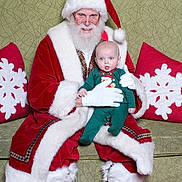 Raymond is registered to the contest to win money with this photo: santa_claus, baby, child, christmas, holiday, red_suit, white_beard, green_onesie, glasses, couch, pillow, snowflake, indoor, portrait, person, smile, festive, gloves, hat, seasonal