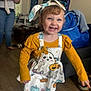 toddler, child, smiling, happy, indoor, barefoot, yellow_shirt, dress, headband, halloween, ghost, pumpkin, floor, toy, furniture, person, living_room, curtains, bag, jeans