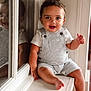 child, toddler, smiling, indoor, reflection, window, overalls, white_shirt, curly_hair, happy, face, sitting, barefoot, skin, light, window_ledge, portrait, young_child, cute, person