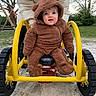 baby, child, onesie, bear_costume, playground, spring_rider, yellow, outdoor, park, sand, trees, adult_hand, happy, cute, smiling, blue_eyes, winter_clothing, person, nature, daytime