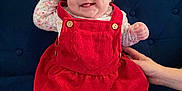 Lily is registered to the contest to win money with this photo: baby, bow, child, couch, cozy, cute, dimples, hand, happy, home, indoor, infant, person, plush, portrait, red_dress, seated, smiling, white_tights, young_child