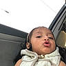 child, toddler, girl, portrait, selfie, car, car_interior, seated, face, eyes, hair, scarf, white_clothing, kissy_face, funny_expression, daylight, window, close_up, casual_photo, person