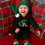 baby, infant, child, smiling, elf_hat, christmas, holiday, plaid, pillow, socks, red_carpet, cozy, festive, portrait, seated, smile, cute, hat, clothing, indoors
