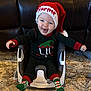 Harper joined the competition — help win amazing prizes! baby, infant, child, santa_hat, knit_hat, smiling, laughing, booster_seat, baby_seat, rug, carpet, leather_couch, holiday_socks, christmas, festive_clothing, indoor, portrait, cute, cheerful, hands_outstretched