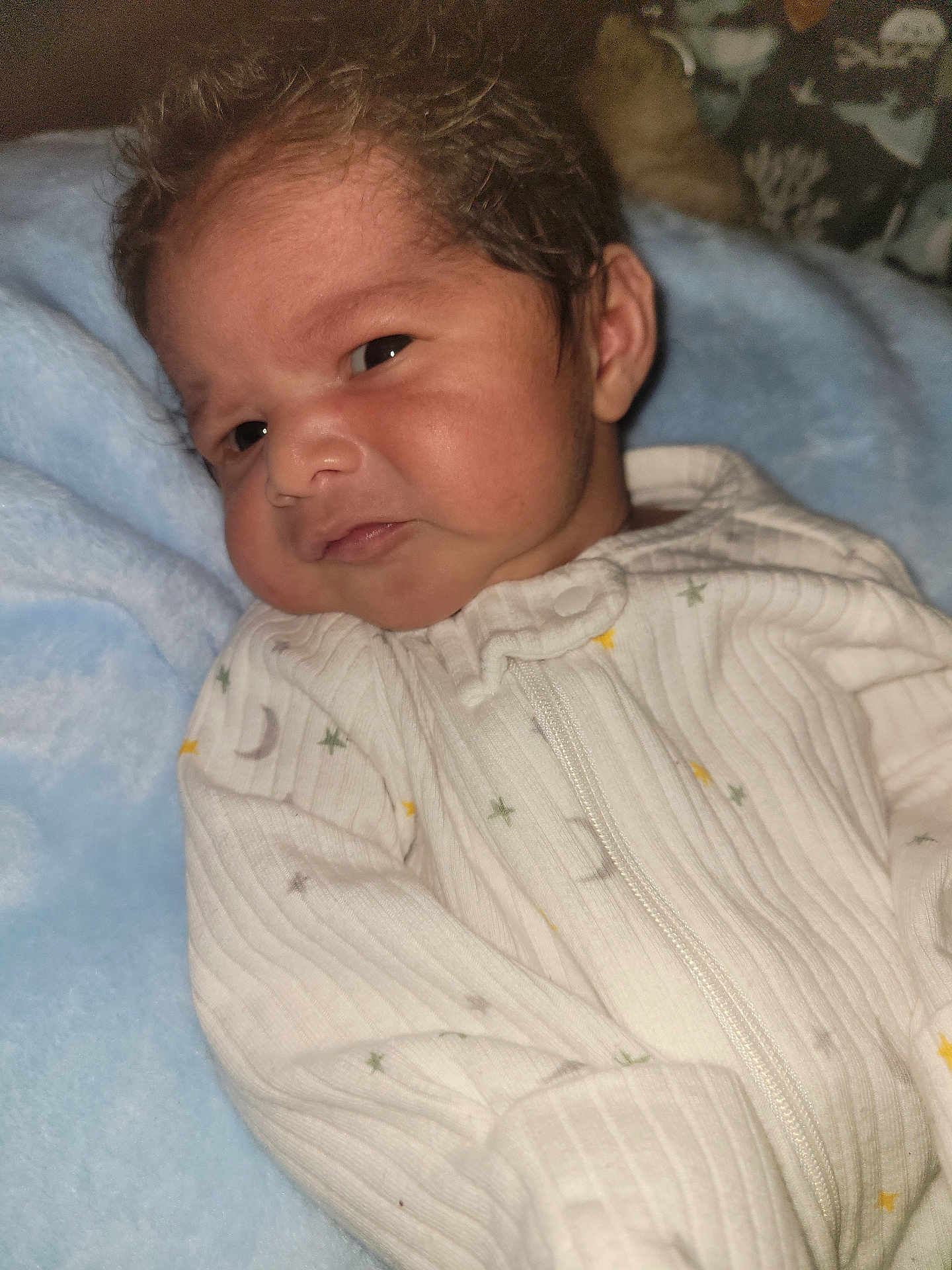 Adriel is registered to the contest to win money with this photo: baby, infant, face, onesie, white_clothing, blue_blanket, newborn, cute, expression, skin, hair, sleepwear, soft_texture, indoors, portrait, child, young, resting, cozy, closeup