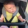 Maisy is registered to the contest to win money with this photo: baby, stroller, yellow_clothing, child, infant, pacifier, blanket, outdoor, sunlight, seatbelt, baby_seat, hand, face, expression, headrest, pink_blanket, toddler, person, safety_harness, closeup