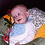 baby, child, rose, flower, bib, white_clothing, cushion, green_cushion, yellow_cushion, red_rose, smile, face, hand, indoor, portrait, cute, sitting, soft_toys, happy, young_child