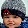 baby, child, hat, pom_pom, knitted_hat, winter_clothing, blue_jacket, rosy_cheeks, outdoor, snow, face, expression, curious, cold_weather, warm_clothing, infant, portrait, cute, closeup, person