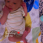 Isaiah is registered to the contest to win money with this photo: baby, infant, child, newborn, lying_down, blanket, bed, striped_onesie, clothing, portrait, face, eyes, hands, feet, indoors, colorful, cozy, sleeping_area, textile, candid
