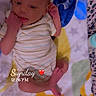 baby, infant, child, newborn, lying_down, blanket, bed, striped_onesie, clothing, portrait, face, eyes, hands, feet, indoors, colorful, cozy, sleeping_area, textile, candid