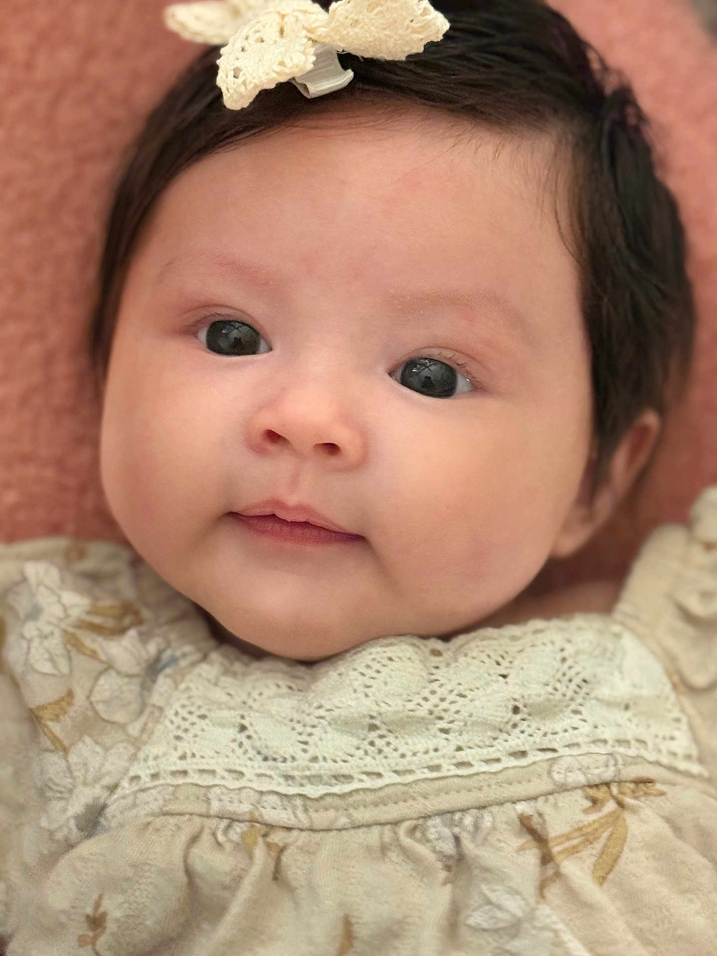 Naomi Luna is registered to the contest to win money with this photo: baby, infant, face, portrait, close_up, child, cute, hair, bow, clothing, fabric, texture, skin, eyes, expression, soft, pink_background, head, newborn, smile