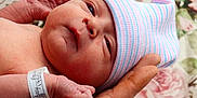 Raelynn joined the competition — help win amazing prizes! adult_hand, baby, blanket, closeup, cute, face, floral_background, hand, hat, hospital_bracelet, infant, newborn, newborn_baby, portrait, resting, skin, sleepy, soft, striped_hat, tiny
