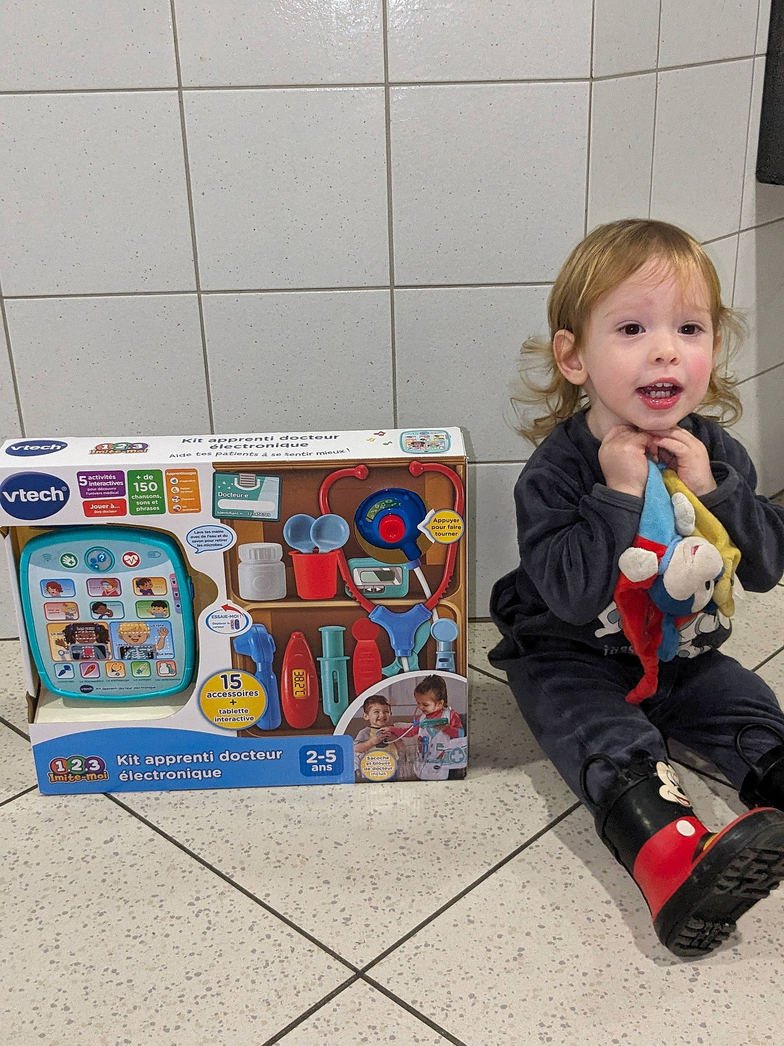 Ghjulianu participe au concours pour gagner de l'argent avec cette photo : baby_toddler_clothing, box, child, flooring, happy, joy, machine, person, play, sitting, sleeve, smile, snack, sock, toddler