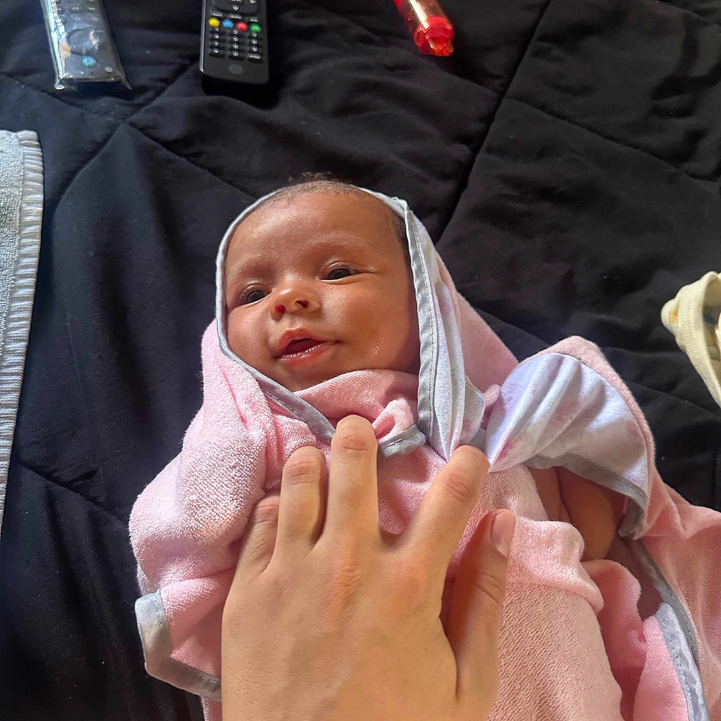 Gianna-Hailey is registered to the contest to win money with this photo: baby, bed, blanket, casual, closeup, comfort, cute, hand, holding, indoor, infant, lighter, person, pink_towel, relaxation, remote_control, rest, skin, small, soft_texture