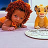 baby, infant, lion_costume, plush_toy, simba, birth_announcement, handwritten, table, orange, cute, child, costume, soft_surface, portrait, indoor, person, toy, face, looking, curious