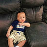 baby, child, infant, couch, sofa, leather, clothing, shirt, shorts, socks, person, indoors, seat, furniture, cute, young, relaxing, casual, expression, small