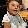 baby, child, smiling, laughing, curly_hair, bib, rocket, stars, indoor, happy, toddler, clothing, face, person, seat, expression, cute, joyful, skin, infant