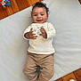 baby, child, smiling, clapping, indoor, toy, mat, wooden_floor, white_socks, beige_pants, long_sleeve_shirt, happy, cute, infant, playtime, flooring, person, portrait, young_child, casual_clothing