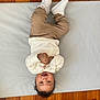 Elohïm a rejoint le concours — aidez-le/la à gagner de superbes lots ! toddler, child, smiling, upside_down, white_shirt, beige_pants, white_sneakers, wooden_floor, soft_mat, toy, happy, indoor, cute, playful, person, portrait, baby, casual_clothing, flooring, infant