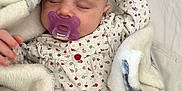 Ellie a rejoint le concours — aidez-le/la à gagner de superbes lots ! baby, sleeping, blanket, pacifier, infant, cozy, soft, cute, child, onesie, patterned_clothing, rest, peaceful, indoor, comfort, closeup, face, hand, nap, warm