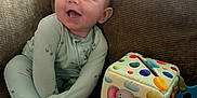 Gianni joined the competition — help win amazing prizes! baby, child, pajamas, smiling, couch, sofa, toy, soft_toy, elephant, colorful, indoor, happy, infant, playful, seated, cute, fabric, home, furniture, portrait