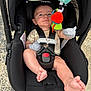 Gianni is registered to the contest to win money with this photo: baby, car_seat, infant, toy, colorful, straps, outdoor, pavement, footwear, cute, child, seat, safety, reaching, clothing, expression, person, baby_toy, black, infant_care