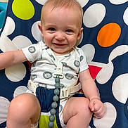 Dallas is registered to the contest to win money with this photo: baby, infant, child, smiling, portrait, seated, indoor, colorful, polka_dot, baby_chair, pacifier, pacifier_clip, onesie, blue_socks, harness, playful, happy, face, closeup, photography