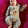 Ezekiel is registered to the contest to win money with this photo: baby, infant, 5_months, onesie, feeding_tube, lying_down, magenta_blanket, wooden_sign, monkey_illustration, cute, curious, hand_raised, foot, face, cheek, clothing, child, indoors, soft_texture, portrait