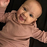 Nyana joined the competition — help win amazing prizes! baby, infant, smile, happy, face, eyes, hand, clothing, ribbed, pink, cute, lying_down, portrait, child, skin, fingertips, expression, young, person, indoors
