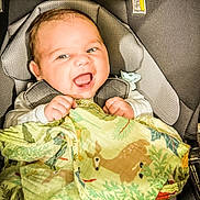 Dru is registered to the contest to win money with this photo: baby, blanket, car_seat, child, closeup, clothing, comfort, cute, deer, fabric, face, green, happy, holding, indoors, infant, pattern, portrait, smiling, young