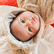 Dru joined the competition — help win amazing prizes! baby, infant, face, hoodie, furry_clothing, bed, pillow, soft_texture, child, cute, portrait, blue_eyes, smile, cozy, indoor, blanket, striped_lining, young_child, cuddly, warm