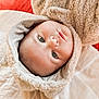 baby, infant, face, hoodie, furry_clothing, bed, pillow, soft_texture, child, cute, portrait, blue_eyes, smile, cozy, indoor, blanket, striped_lining, young_child, cuddly, warm