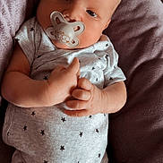 Soan participe au concours pour gagner de l'argent avec cette photo : baby, child, clothing, comfort, cushion, cute, face, hand, head, indoors, infant, newborn, onesie, pacifier, person, portrait, resting, skin, soft, star_pattern