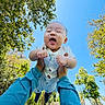 baby, blue_sleeves, child, cute, daylight, grass, greenery, hands, happy, joyful, nature, outdoor, park, person, playing, sky, smiling, sunflare, sunlight, trees