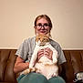 Bandaid is registered to the contest to win money with this photo: brown_couch, calm, casual_clothing, cat, couch, domestic_cat, furniture, glasses, holding, home, indoor, orange_cat, pants, person, pet, portrait, relaxed, short_sleeve_shirt, sitting, white_cat