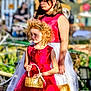 child, children, flower_girl, dress, red_dress, white_skirt, basket, curly_hair, blonde_hair, dark_hair, outdoor, garden, sunlight, grass, footwear, portrait, person, event, ceremony, holding