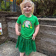 Sophia joined the competition — help win amazing prizes! child, girl, toddler, unicorn_shirt, green_shirt, green_skirt, pigtails, smile, sandals, outdoor, stone_wall, railing, concrete_ground, bushes, plants, porch_steps, portrait, person, happy, casual_clothing