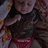 baby, sleeping, blanket, camo_shirt, pink_diaper, child, infant, face, closed_eyes, peaceful, human, person, indoor, soft_texture, cute, resting, portrait, cozy, wrapped, small