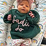 Sadie joined the competition — help win amazing prizes! baby, infant, headband, bow, knitted_sweater, green_sweater, floral_pants, pink_socks, rainbow_pattern, cushion, baby_bedding, soft_toys, indoors, portrait, cute, lying_down, child, newborn, cozy, colorful