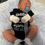 Hunner is registered to the contest to win money with this photo: baby, newborn, pacifier, onesie, mittens, socks, blanket, sleeping, infant, clothing, face, person, cute, resting, soft_texture, blue, white, pattern, comfort, indoors