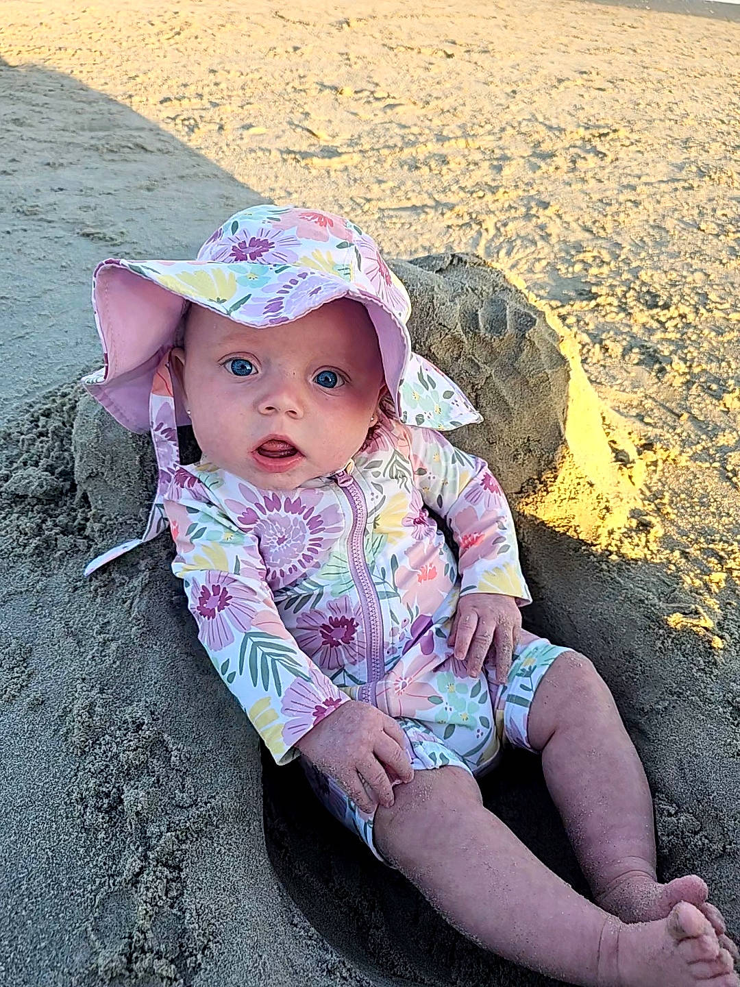 Everly joined the competition — help win amazing prizes! baby, baby_toddler_clothing, beach, child, cool, fashion_accessory, fun, grass, happy, hat, headwear, human_leg, landscape, people_in_nature, person, sand, sitting, skin, sun_hat, thigh