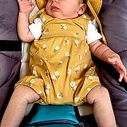 Alice participe au concours pour gagner de l'argent avec cette photo : baby, infant, sleeping, hat, romper, yellow_clothing, floral_pattern, padded_seat, teal_cushion, baby_clothes, relaxing, cute, child, person, indoor, skin, hand, foot, face, resting