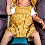 baby, infant, sleeping, hat, romper, yellow_clothing, floral_pattern, padded_seat, teal_cushion, baby_clothes, relaxing, cute, child, person, indoor, skin, hand, foot, face, resting