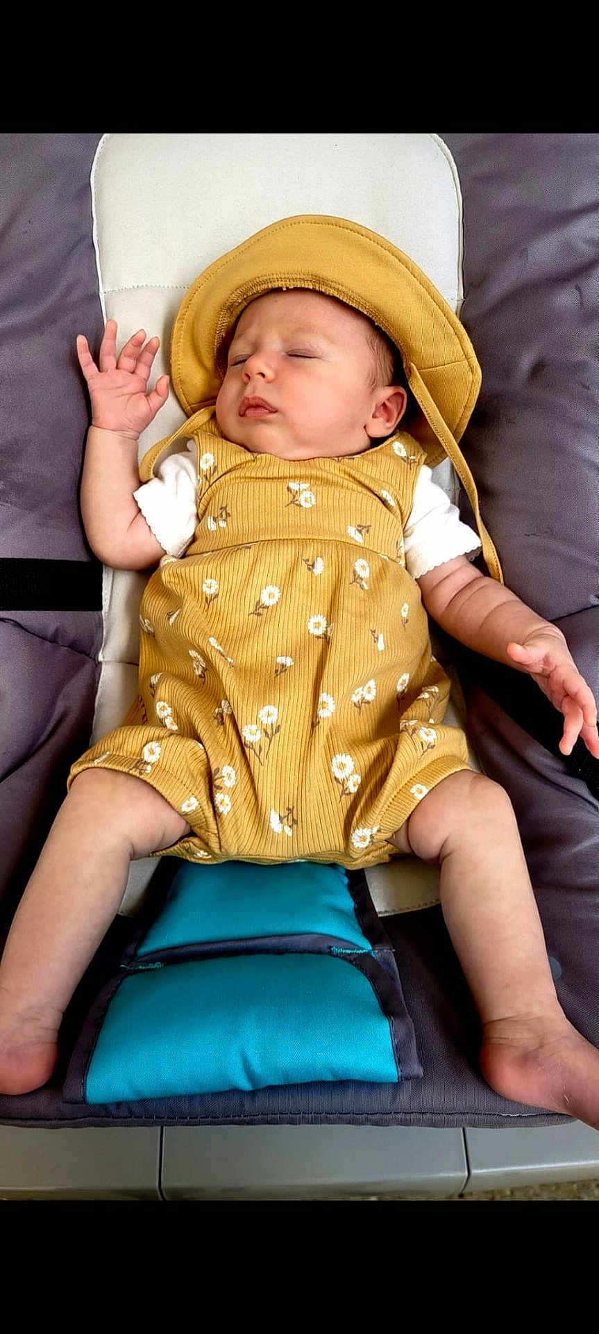 Alice participe au concours pour gagner de l'argent avec cette photo : baby, infant, sleeping, hat, romper, yellow_clothing, floral_pattern, padded_seat, teal_cushion, baby_clothes, relaxing, cute, child, person, indoor, skin, hand, foot, face, resting